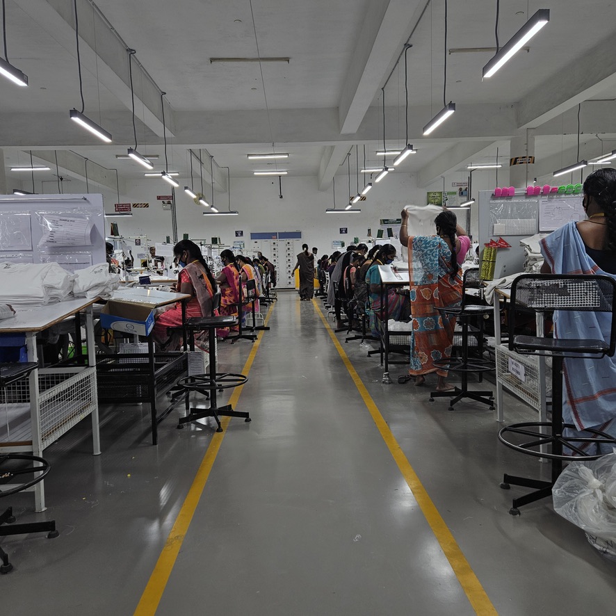 Workers along aisle of stitching floor during visit